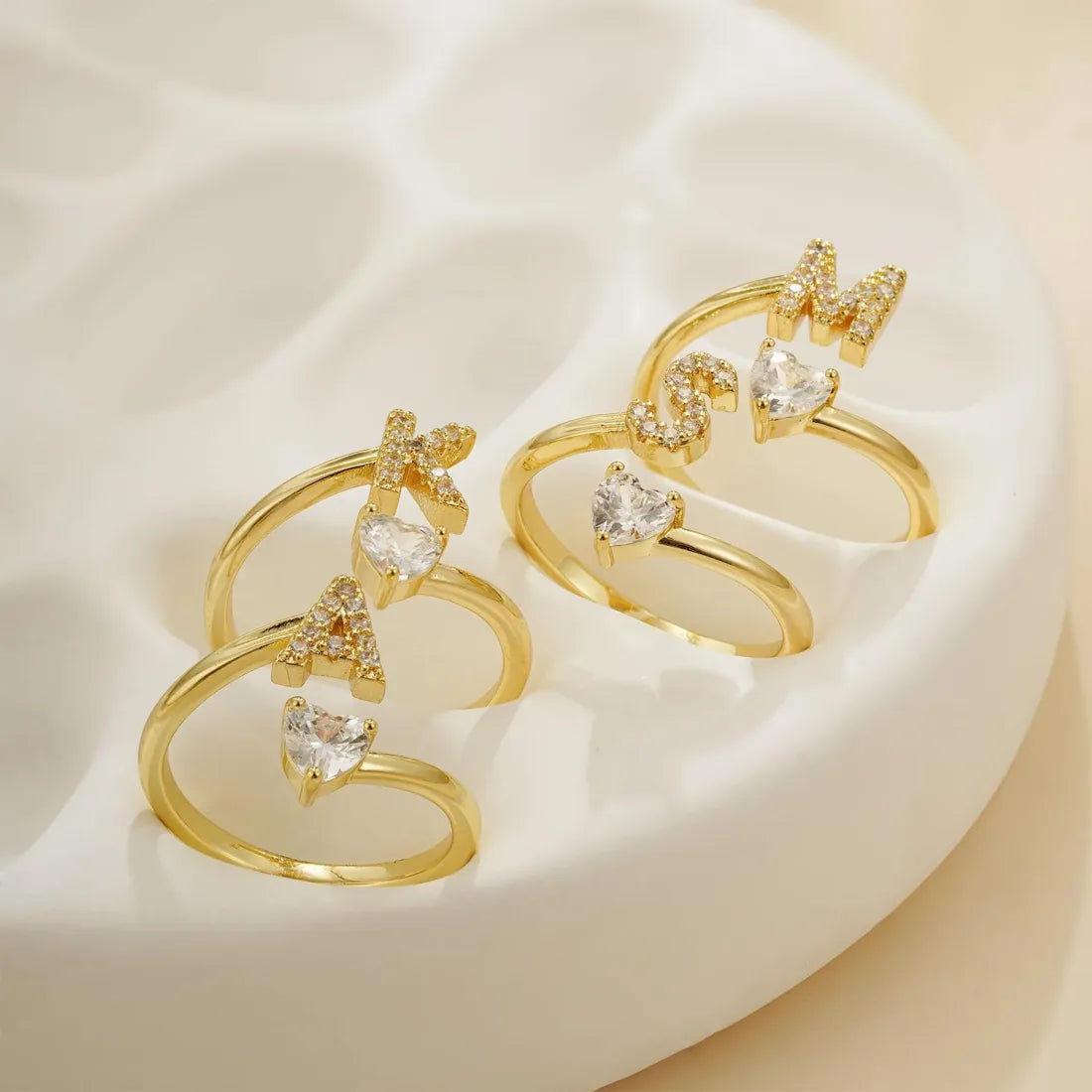 Three rings with different initials on a ceramic plate.
